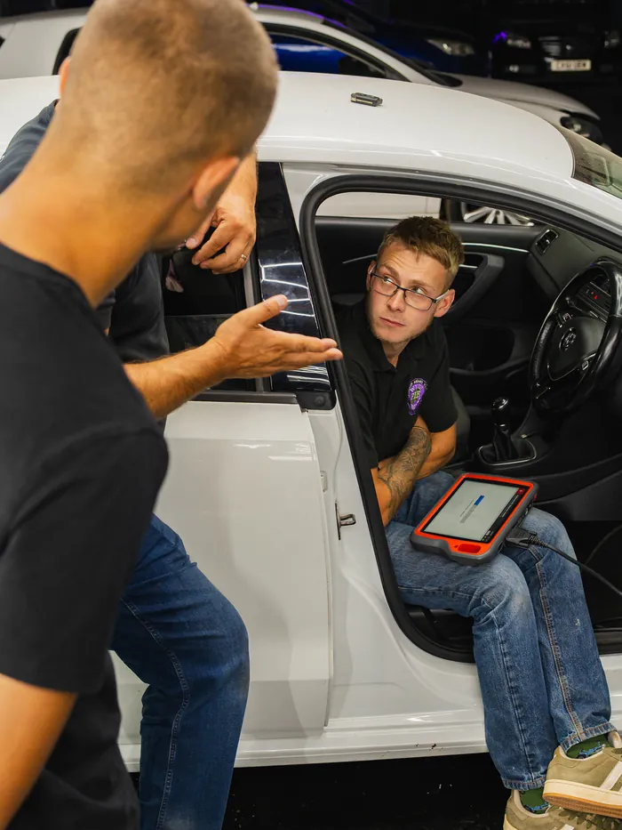 A student programs a key from the driver’s seat while a trainer talks him through it