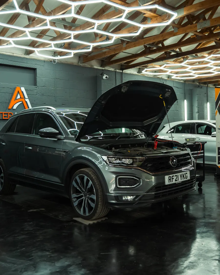 The Alter Academy workshop under hexagon lights: a VW with its bonnet up and a line of cars ready for training
