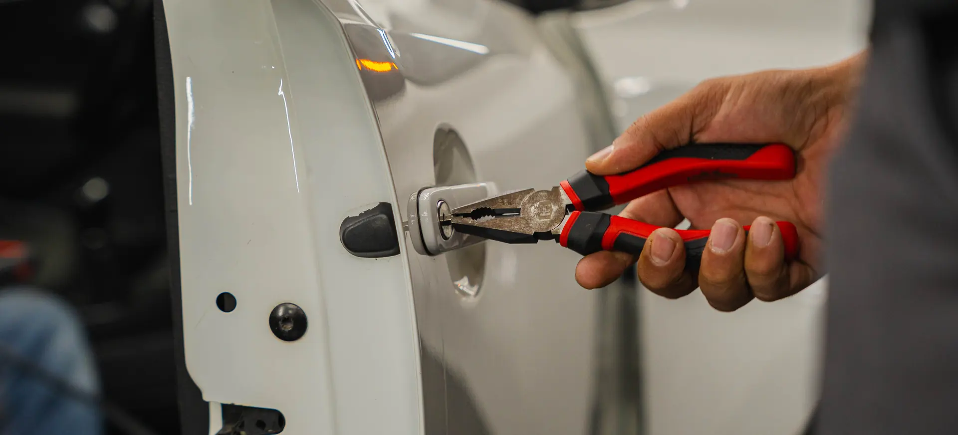 A lock tool worked into a white car door during vehicle entry training