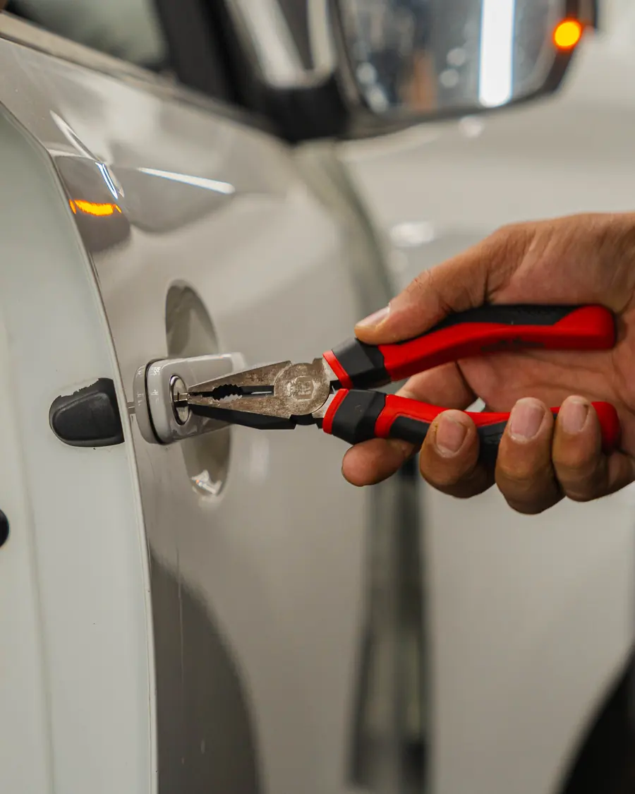 A lock tool worked into a white car door during vehicle entry training