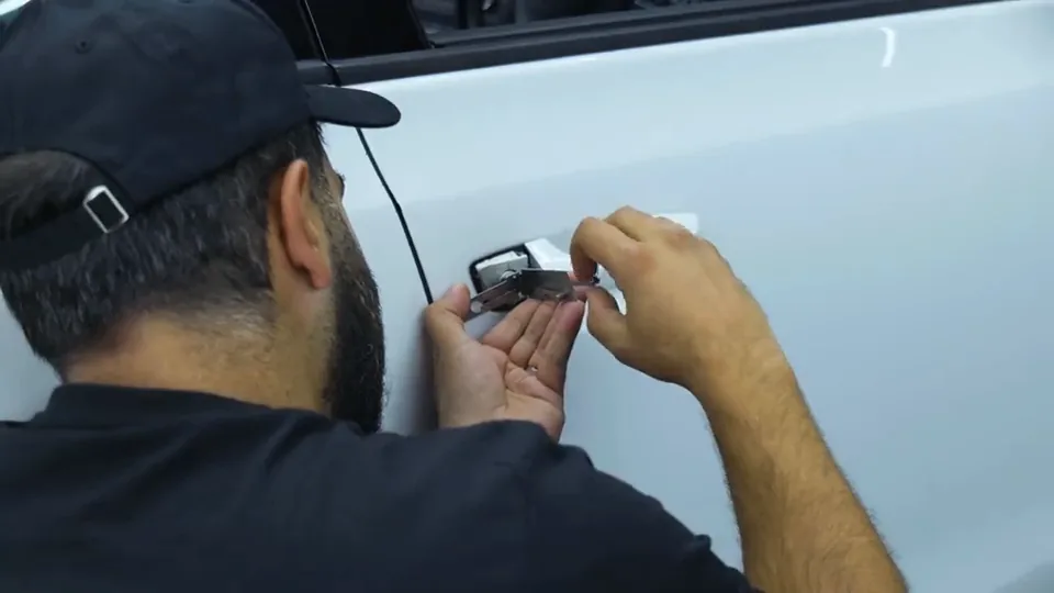 Close-up of a trainee picking a car door lock with a lock pick tool
